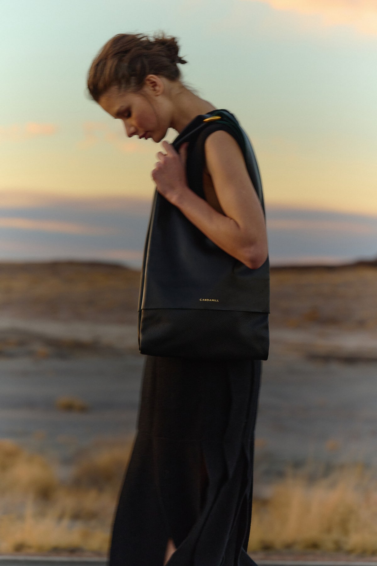 Side view of a model wearing The Collector tote in Black leather and Gold hardware