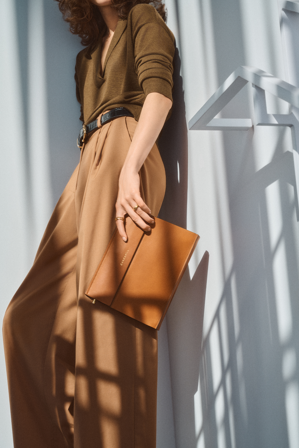 Model carrying the Low Rise bag in Saddle leather as a clutch