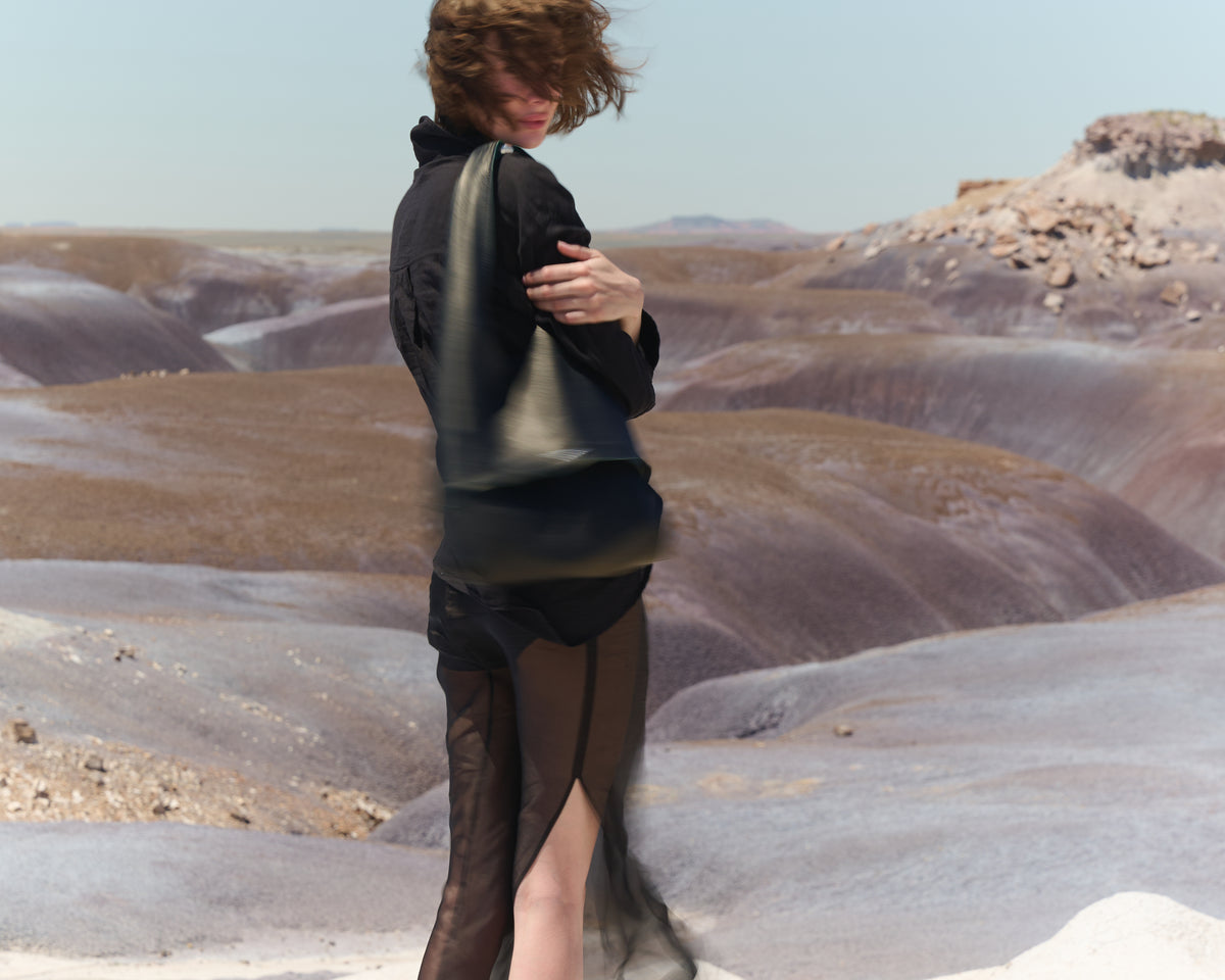 Model wearing The Collector tote in Black leather in a rocky landscape