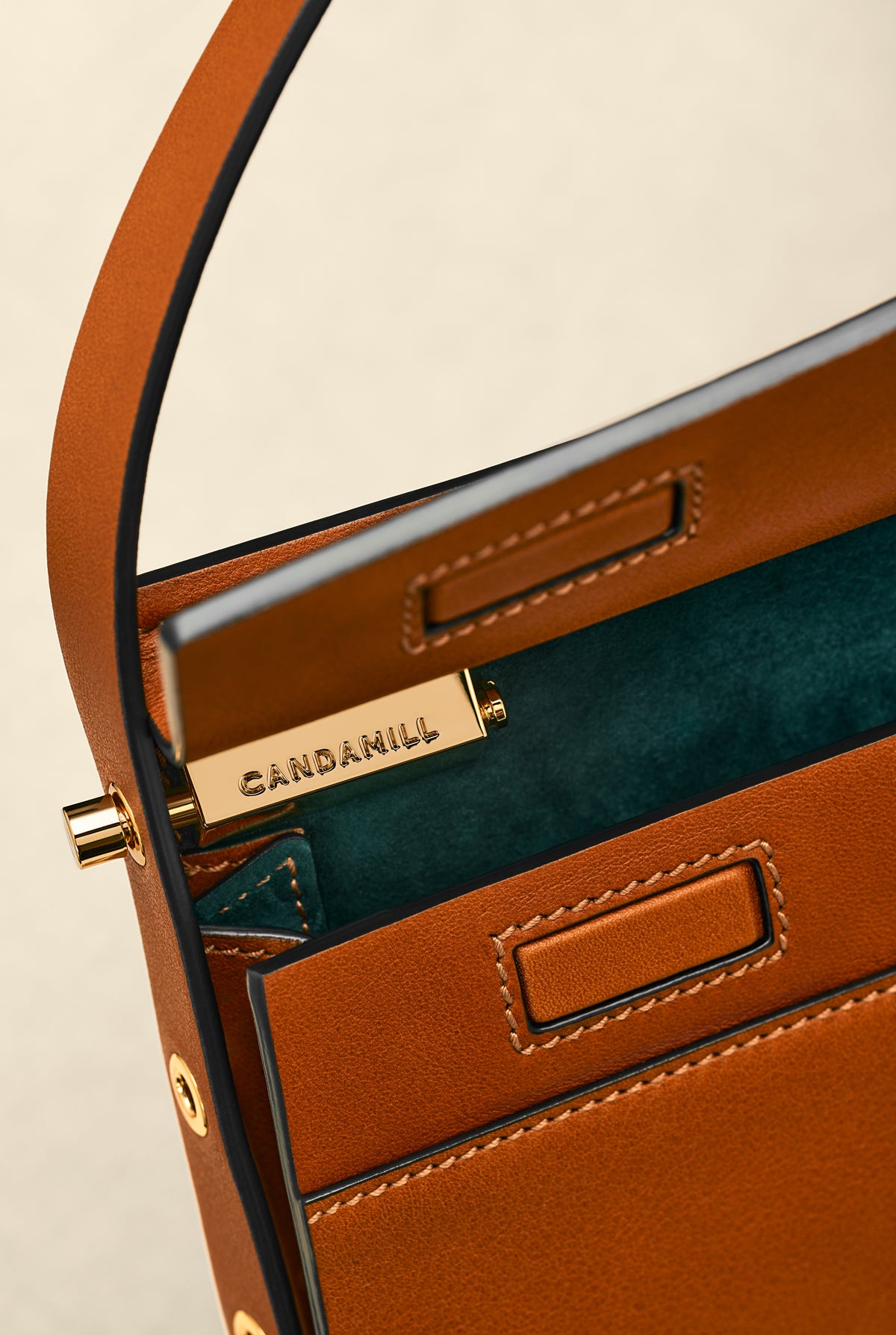 Low Rise in Saddle leather opened to show gold hardware and green suede lining
