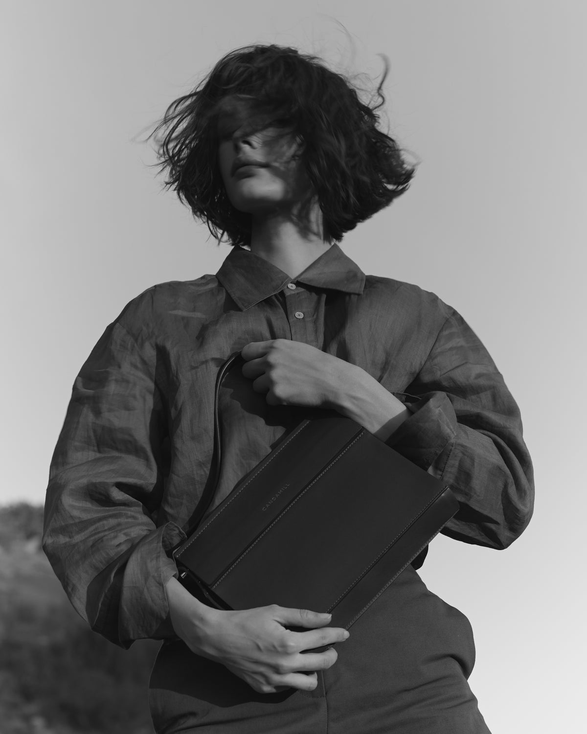 Black-and-white portrait of a model holding the Low Rise bag in Black