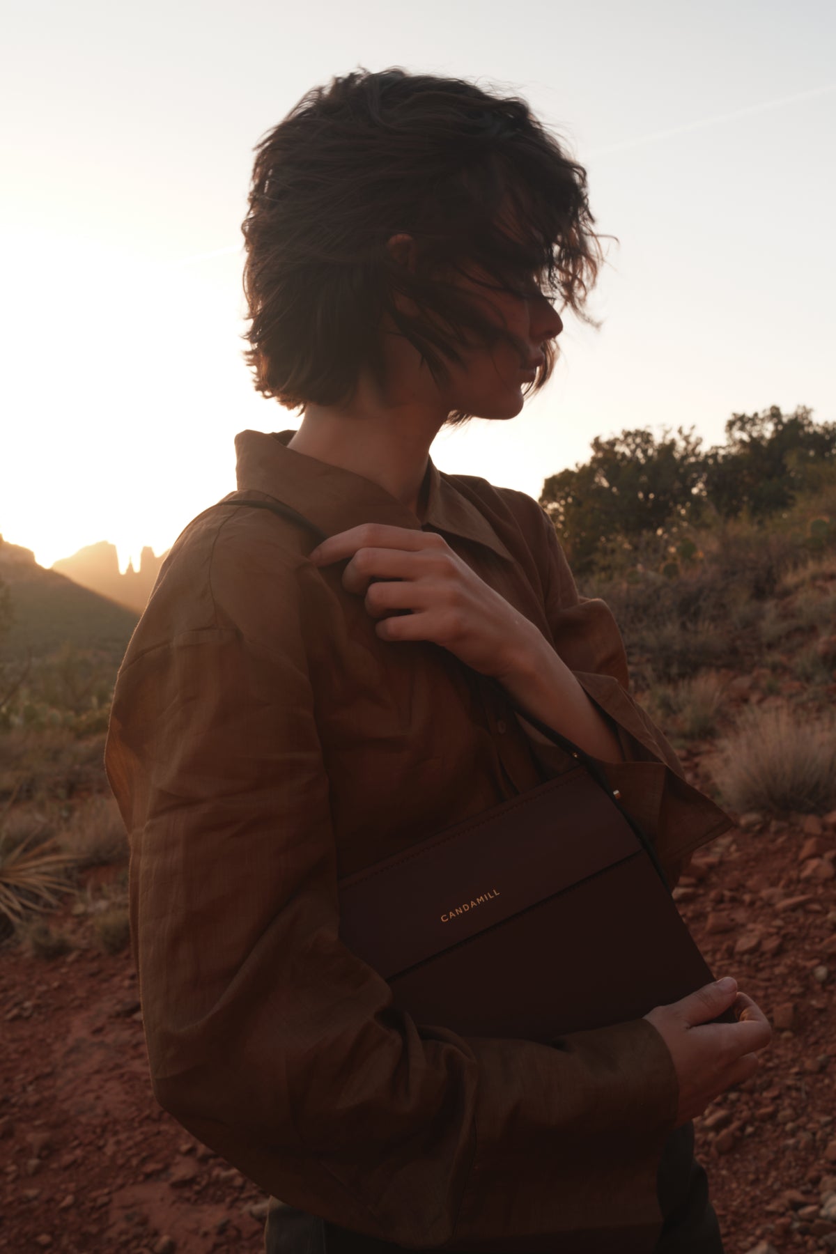 Model holding the Low Rise bag in Cacao leather at sunset