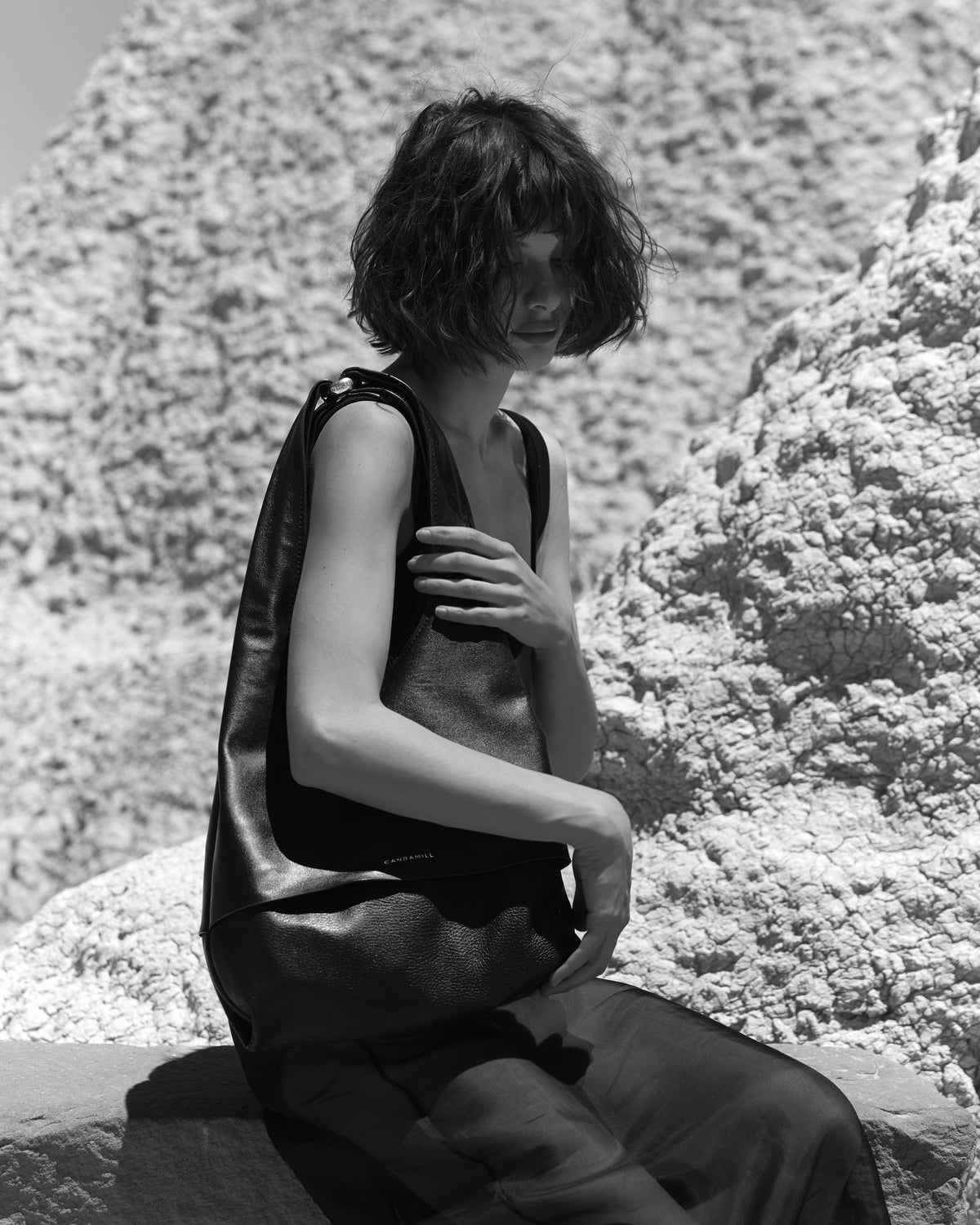 Black-and-white portrait of a seated model wearing The Collector Silver tote