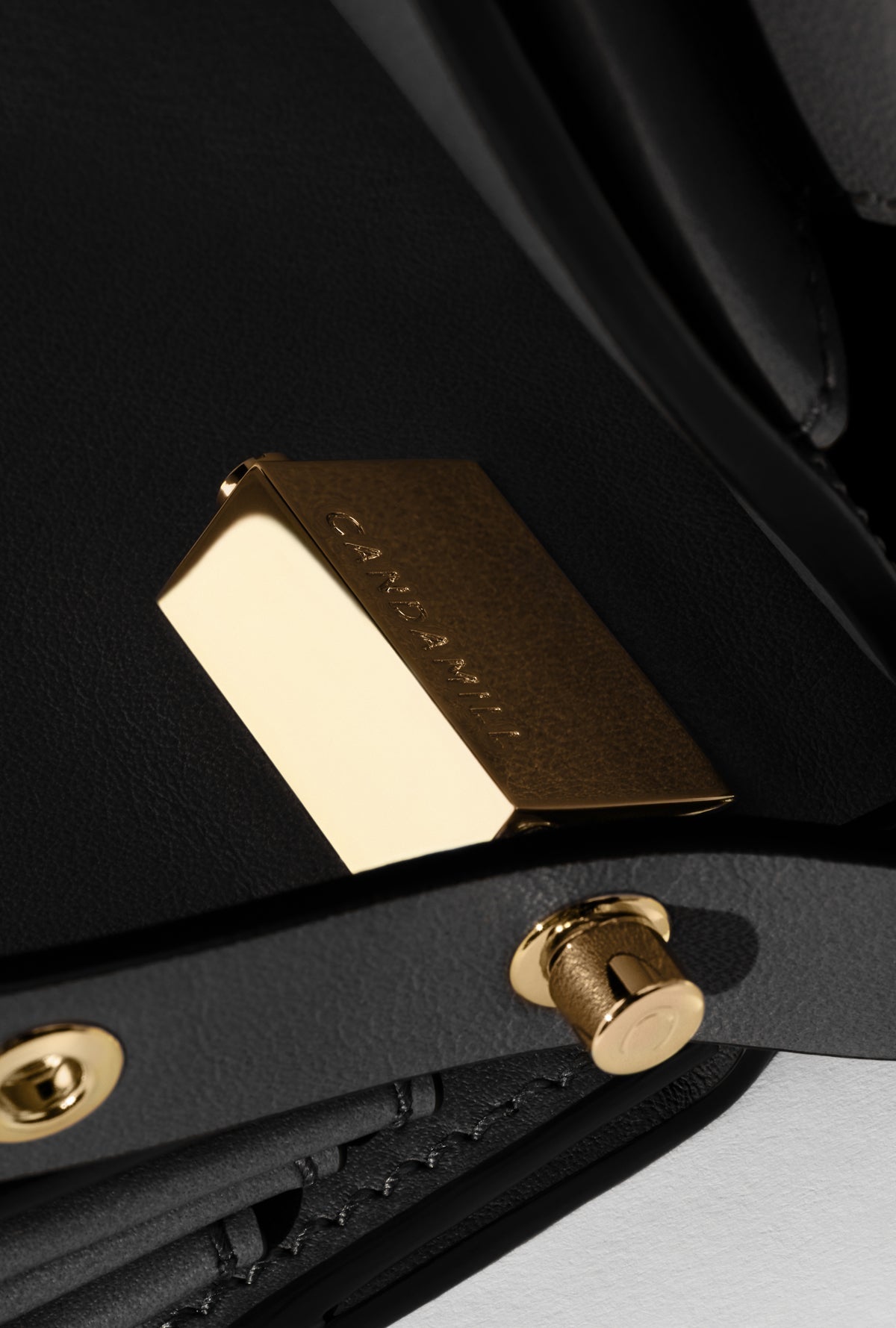 Close-up of High Rise Black leather, triangular gold hardware and strap fastening